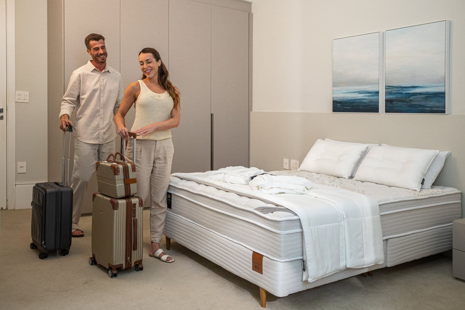 Casal com malas de viagem ao lado da cama Simmons Geocities