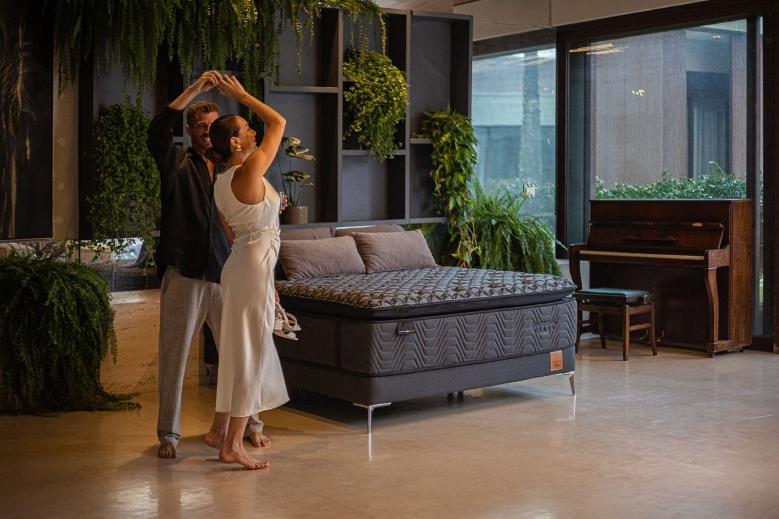 Casal dançando entre a cama Simmons Black e o piano