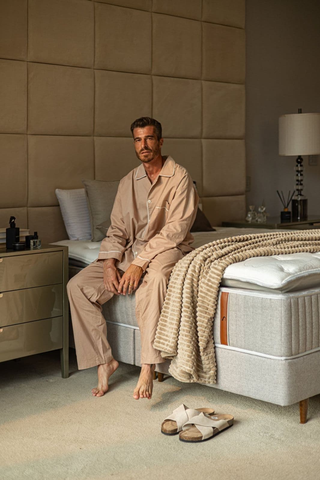 Homem de pijama sentado na beira da cama Simmons pela manhã