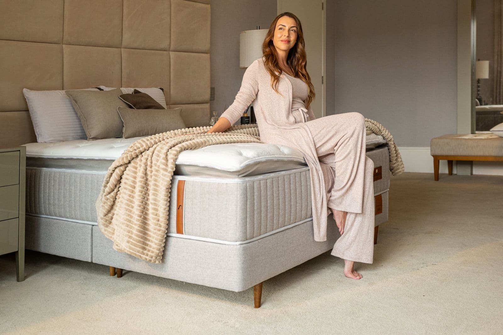 Mulher sentada na cama Simmons de faixa lateral cinza