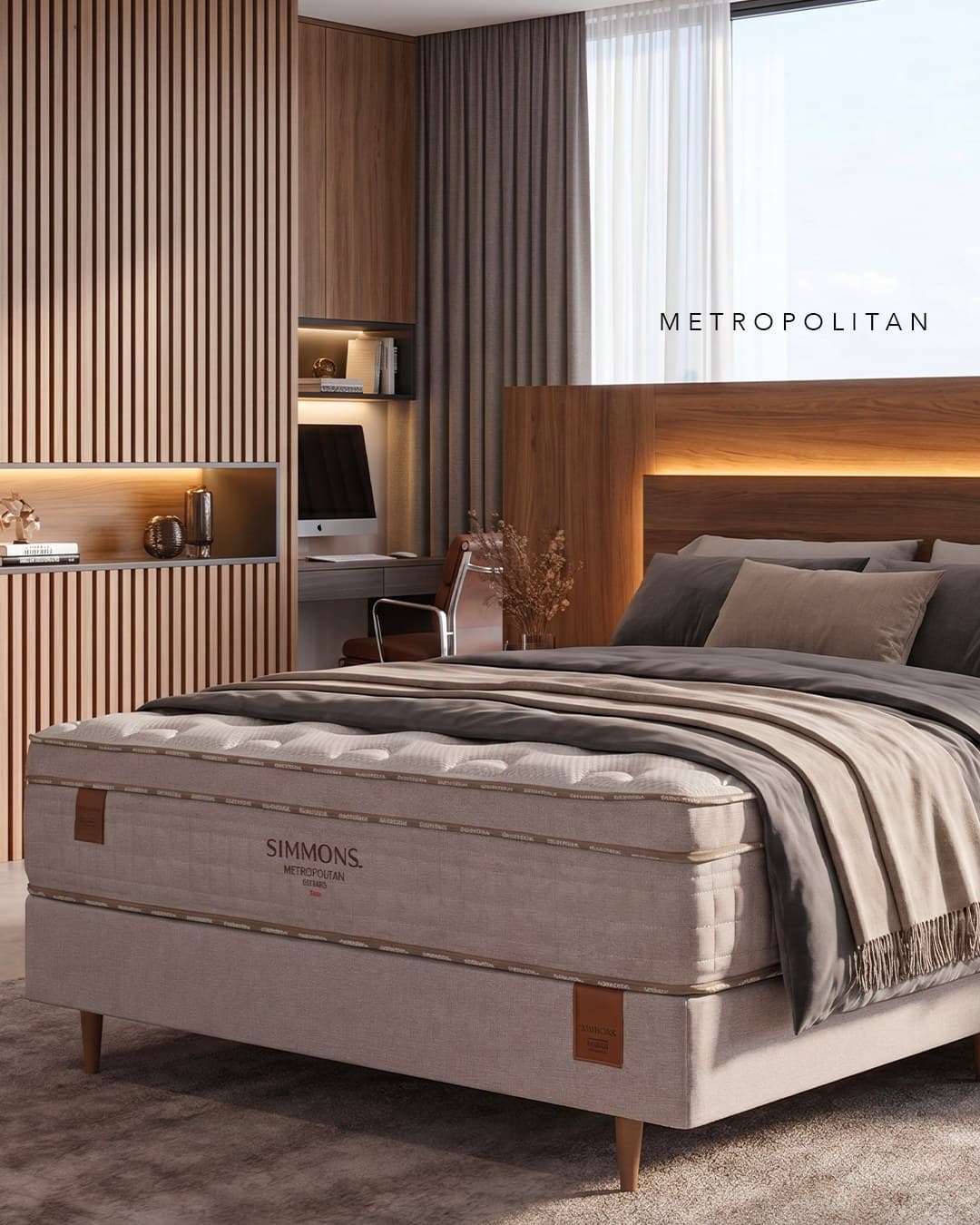 Conjunto Simmons Metropolitan visto em três quartos: pillow top matelassê, faixa lateral com a fita Simmons e a base do box sobre pés de madeira