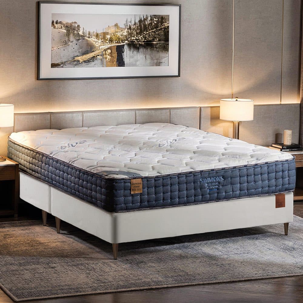 Conjunto Simmons Blue Ocean montado em quarto de tons neutros, com abajures acesos dos dois lados da cama